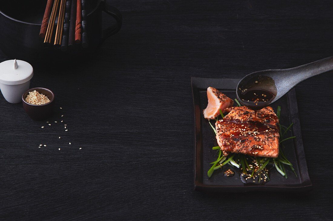 Salmon being drizzled with a sesame and teriyaki sauce