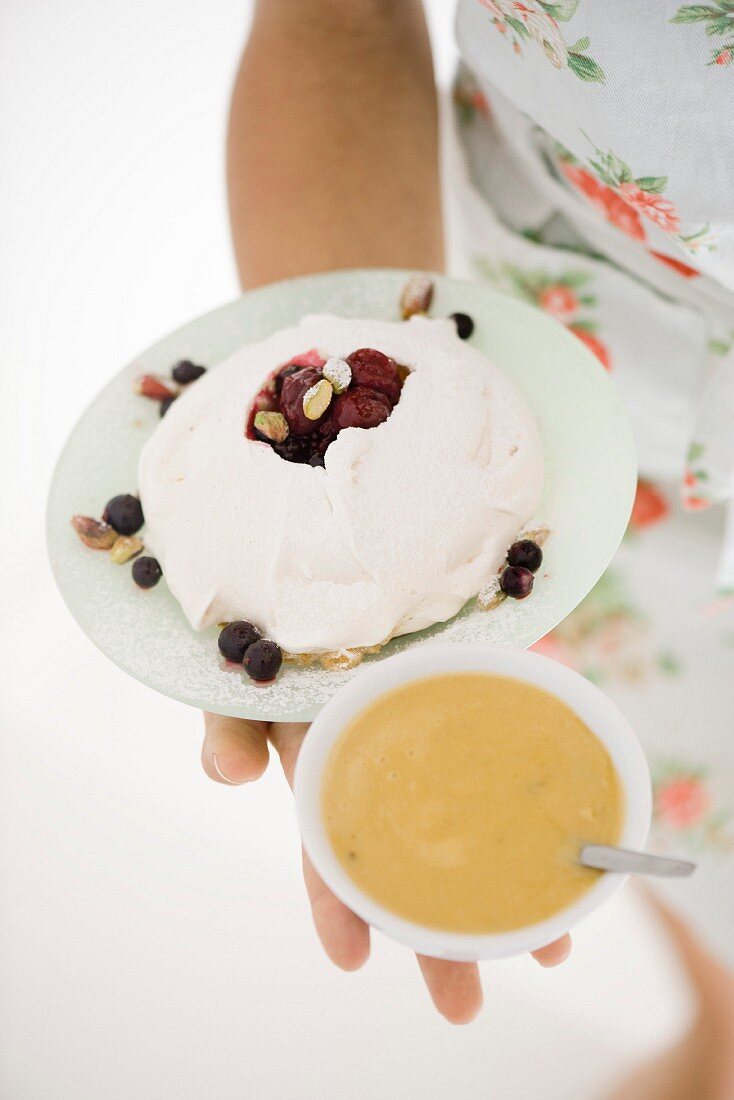 Frau hält Baiser mit Beeren und Kardamomcreme