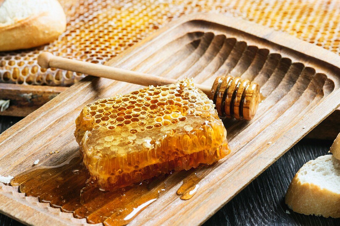 Honeycomb with a honey spoon in an old wooden bowl