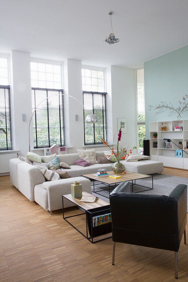 Bright interior with sofa, retro leather armchair and delicate coffee tables