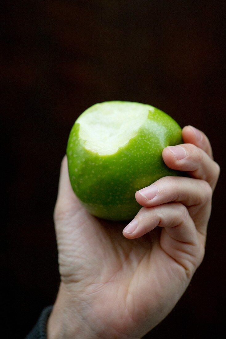 Hand hält angebissenen Apfel