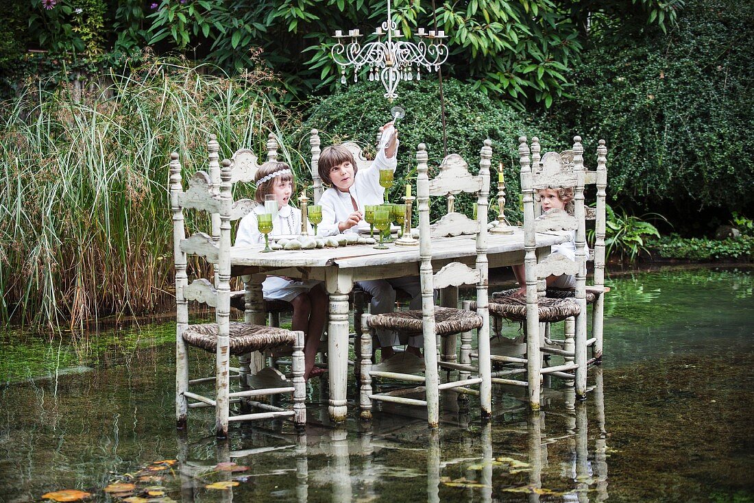 Children sitting at chair in middle of pond