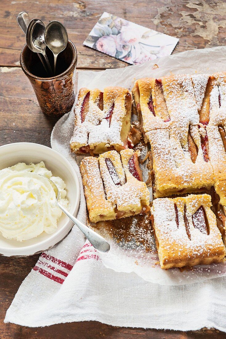 Pflaumen-Kardamom-Kuchen mit Puderzucker und Sahne