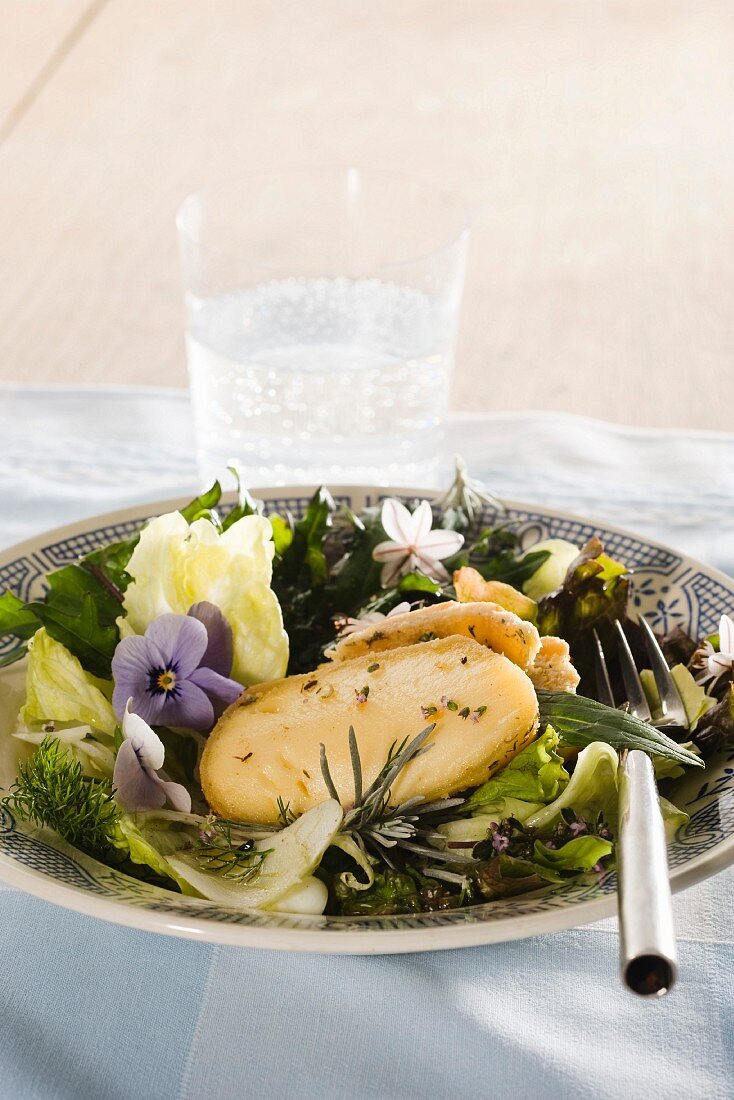 Weichkäse im Blätterteigmantel auf Blattsalat mit Essblüten