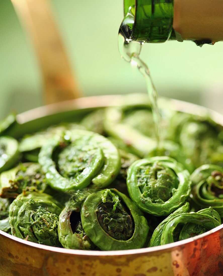 Wine being poured over fiddleheads