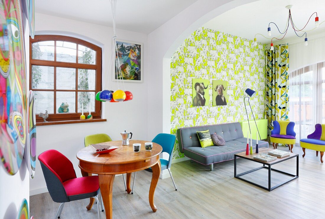 Colourful living area with patterned wallpaper in retro interior with antique dining table