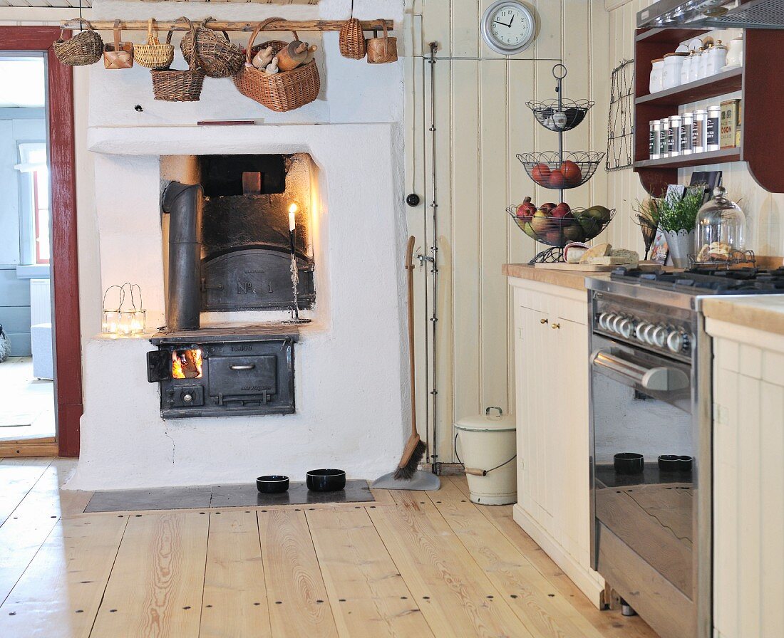 Rustic kitchen with plain wooden floor and basket hung over bricked-in, wood-fired oven