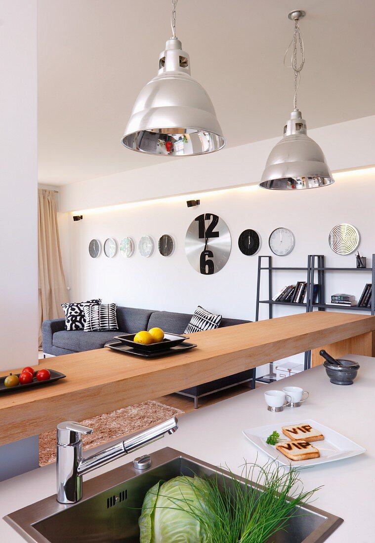 Island counter with integrated sink, minimalist breakfast bar and industrial-style pendant lamps with metal lampshades