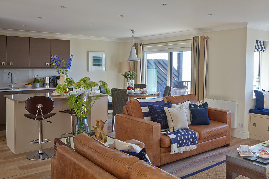 Open-plan living area with brown leather sofas and kitchen with an island