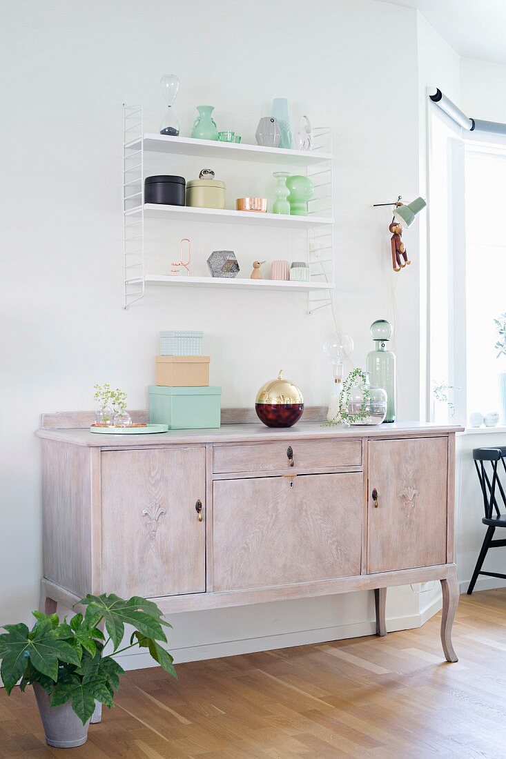 Old bottles and pastel boxes on wall-mounted shelves and vintage cabinet