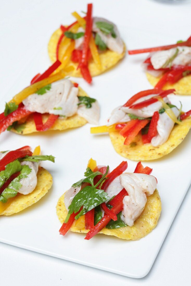 Potato crisps topped with fish, pepper strips and parsley