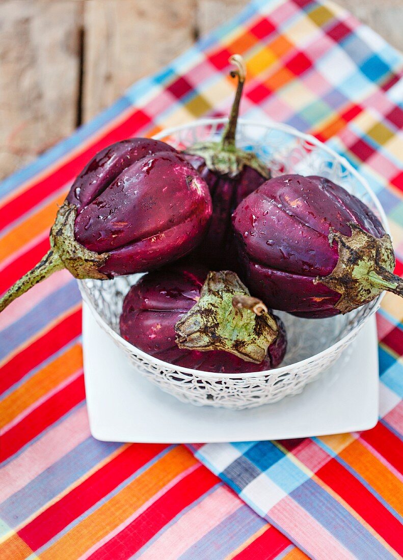 Fresh aubergines in a bowl on a wooden table