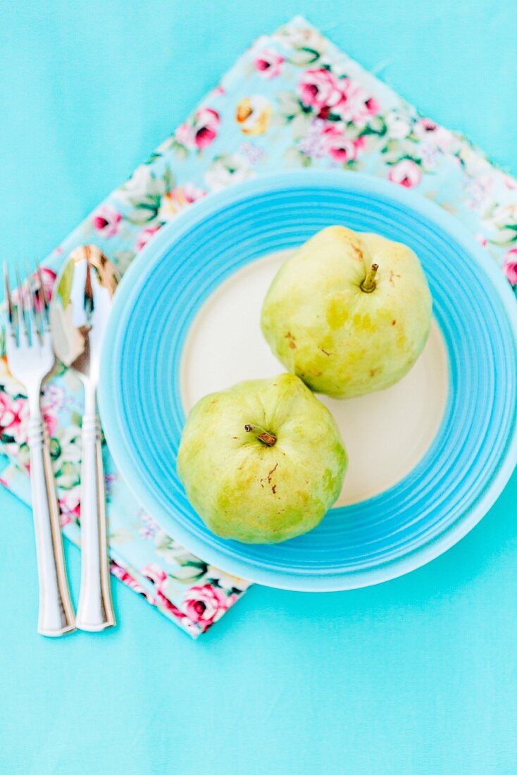 Fresh guavas on a light blue surface with floral-patterned napkins