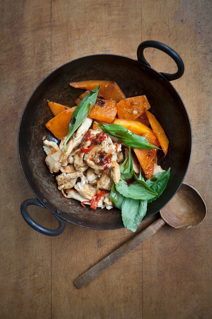 Chicken with pumpkin and basil in a wok