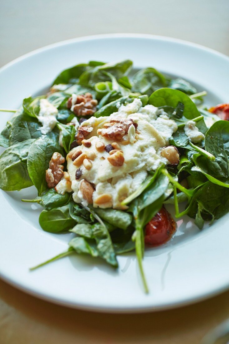 Spinach salad with hummus dressing, tomatoes and nuts
