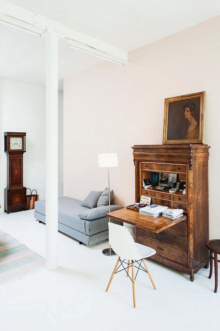 Classic chair at bureau and grey chaise in background in minimalist loft apartment