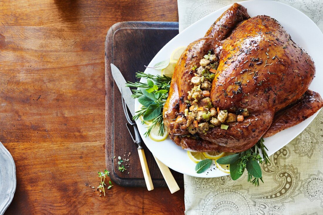 Stuffed roast turkey on a bed of herbs and lemons