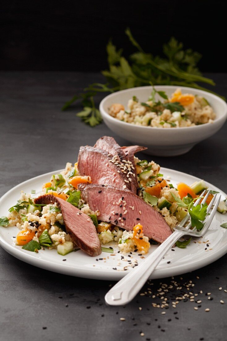 Roast lamb fillet on a bed of couscous with cucumber and dried apricots