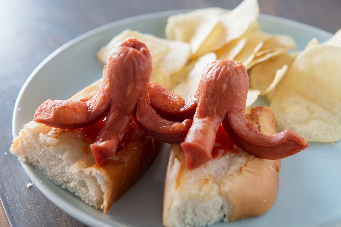 Oktopusförmige Würstchen auf Brötchen mit Ketchup und Kartoffelchips