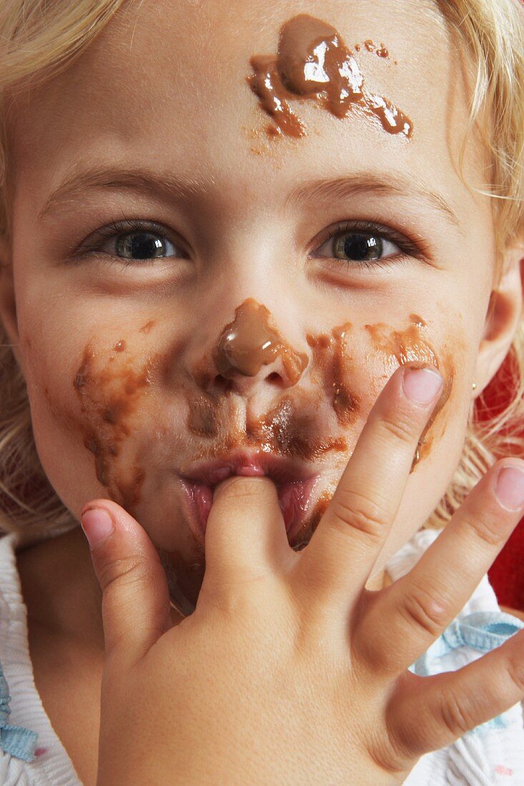 A little girl with chocolate sauce all over her face