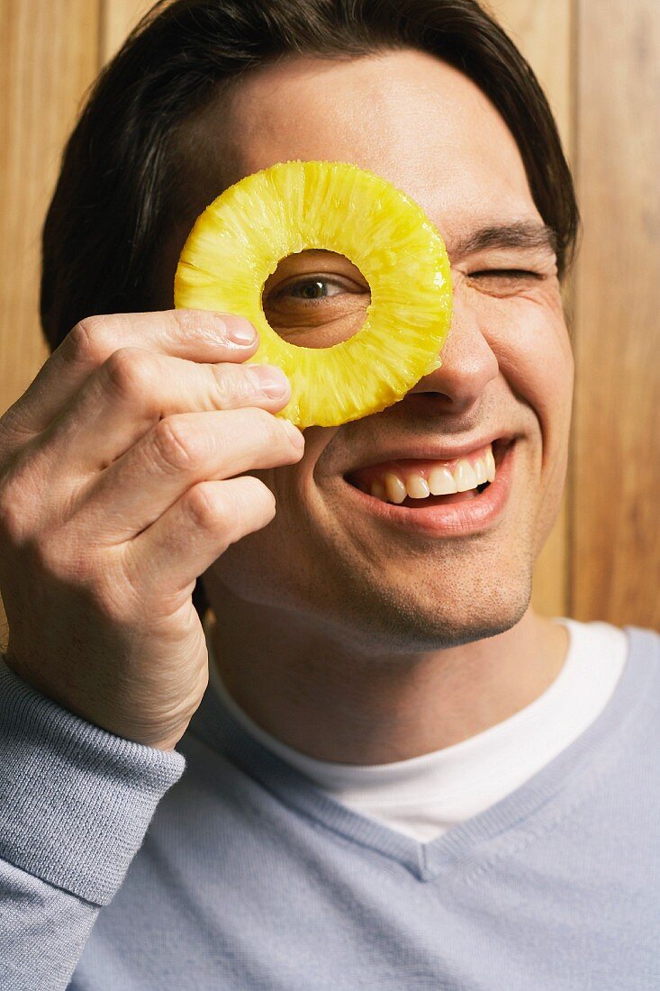 A man looking through a slice of pineapple
