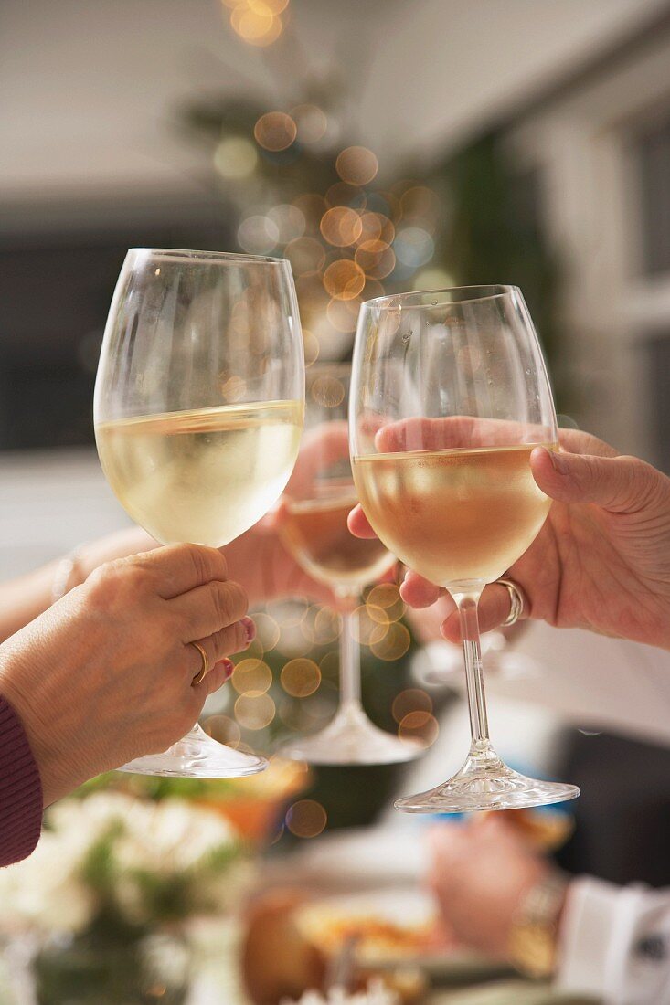 Hands raising glasses of white wine