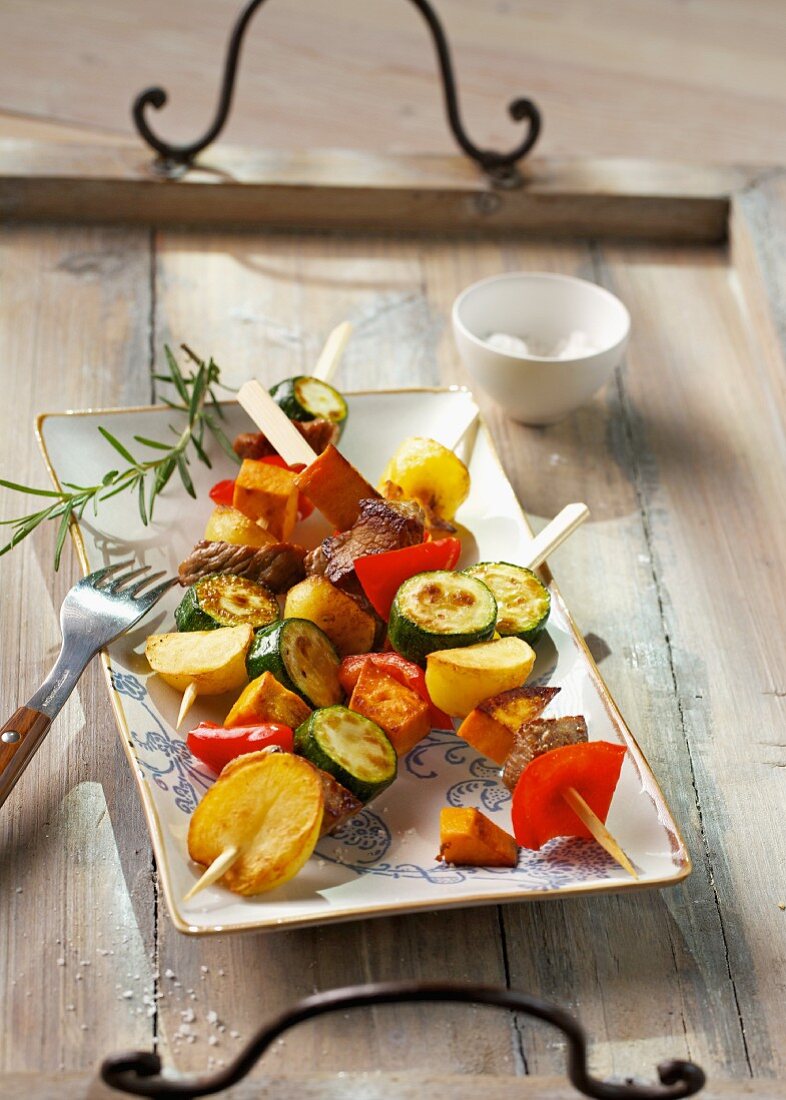 Marinated meat skewers with potatoes and colourful vegetables