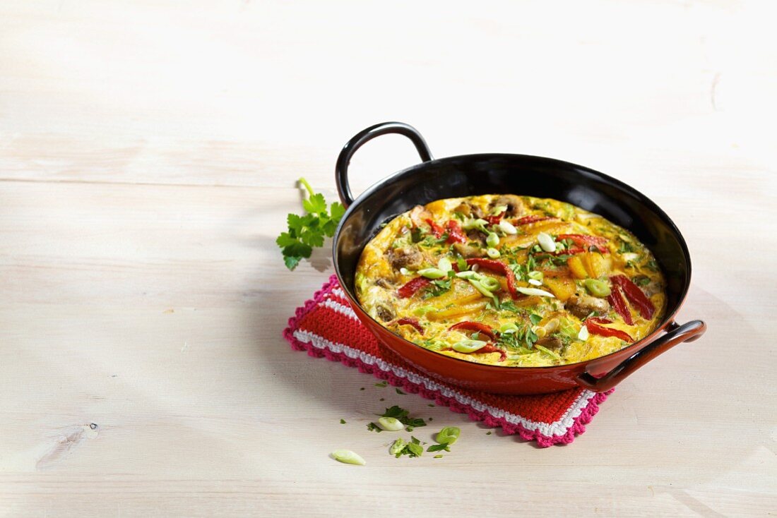 A colourful oven-baked tortilla with mushrooms, red peppers and spring onions