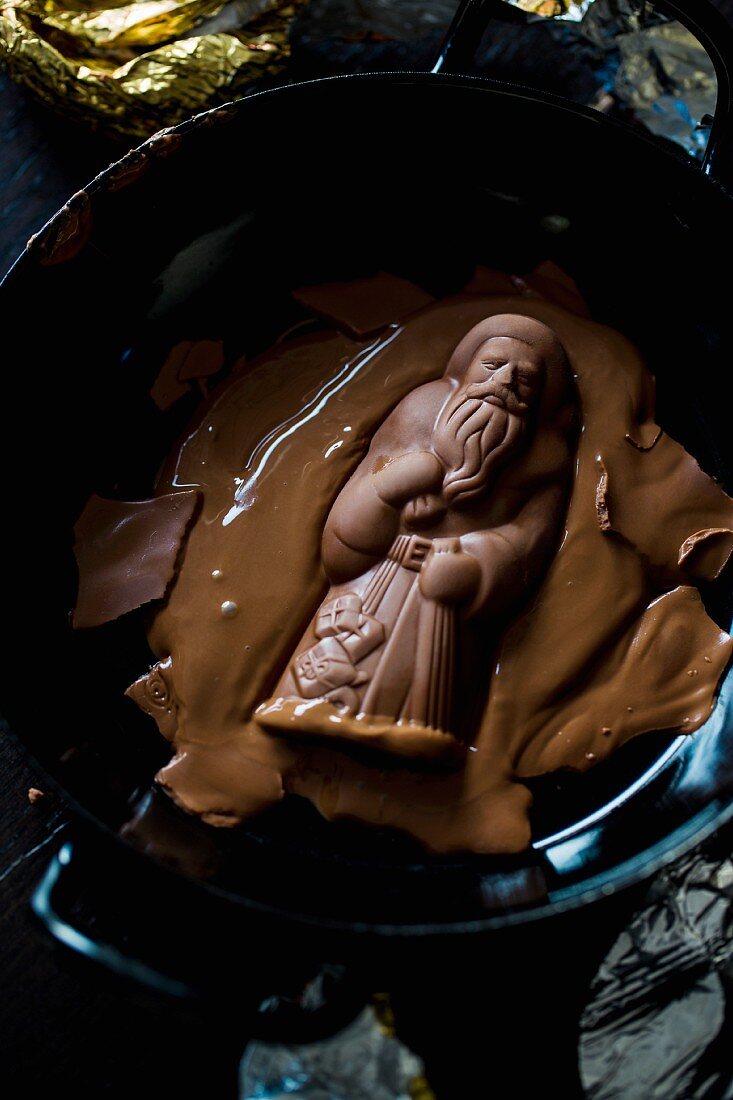 A chocolate Father Christmas being melted to be used for chocolate cake