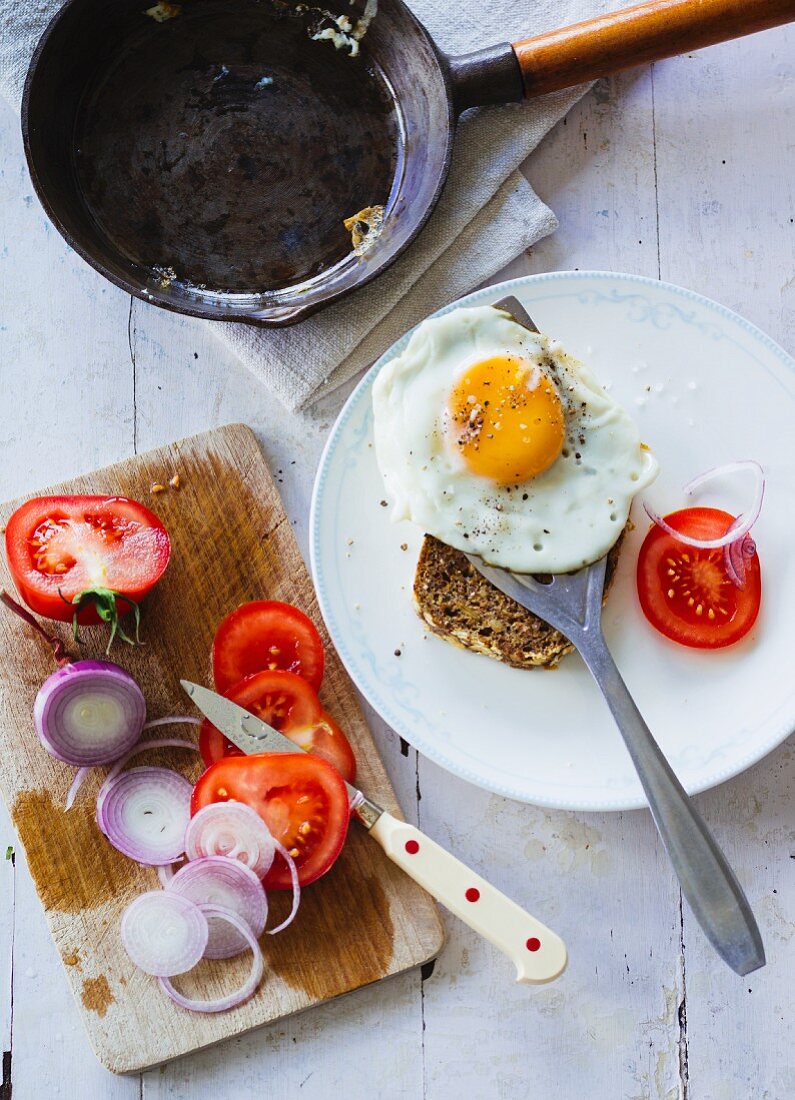 Rye bread with a fried egg, red onions and fresh tomatoes