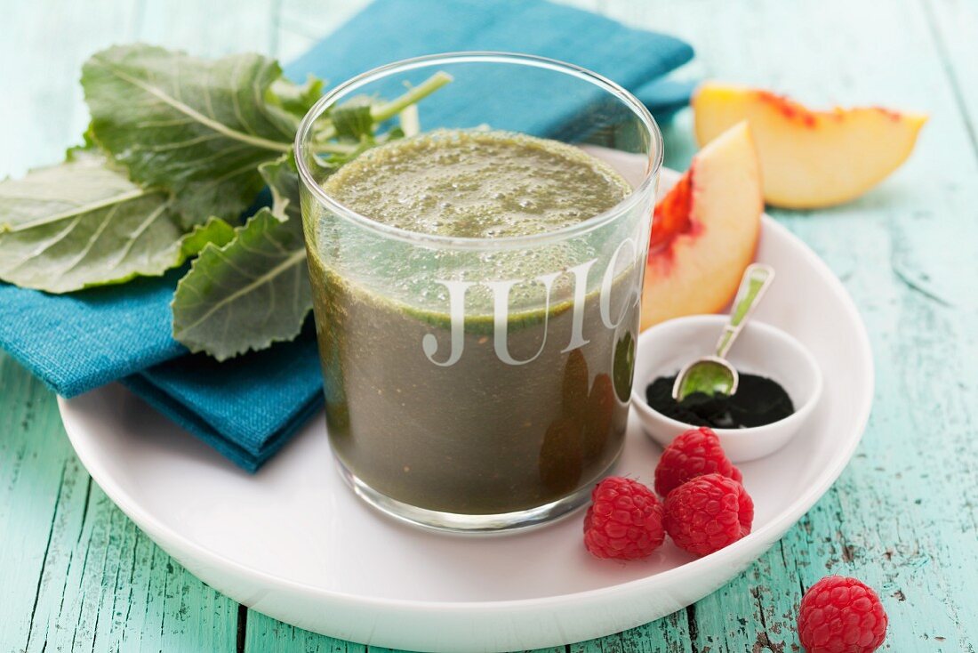 A peach smoothie made with raspberries, spinach, kohlrabi leaves and spirulina