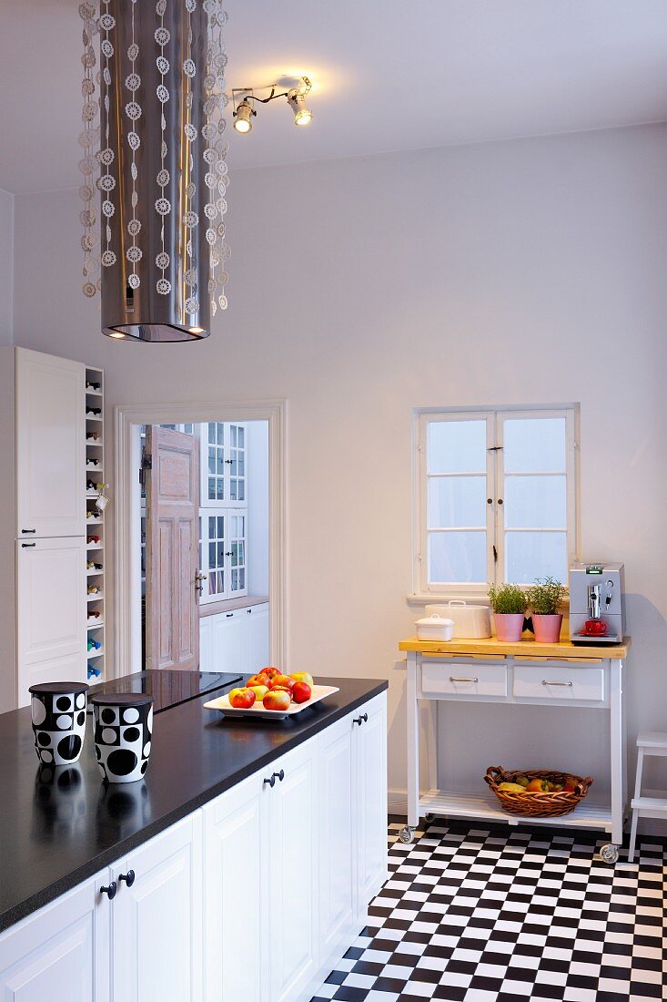 Minimalist, black and white kitchen with chequered floor and modern extractor hood