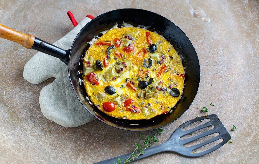 French vegetable omelette with cherry tomatoes, artichoke hearts and black olives