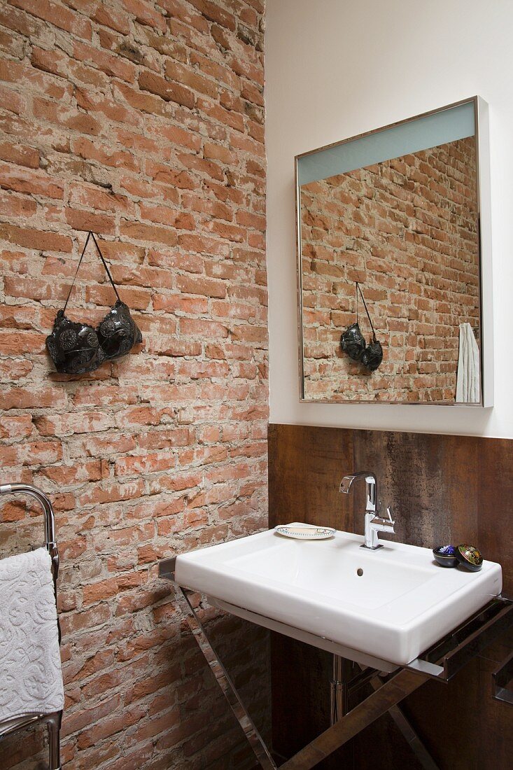 Sink with chrome base frame next to exposed brick wall