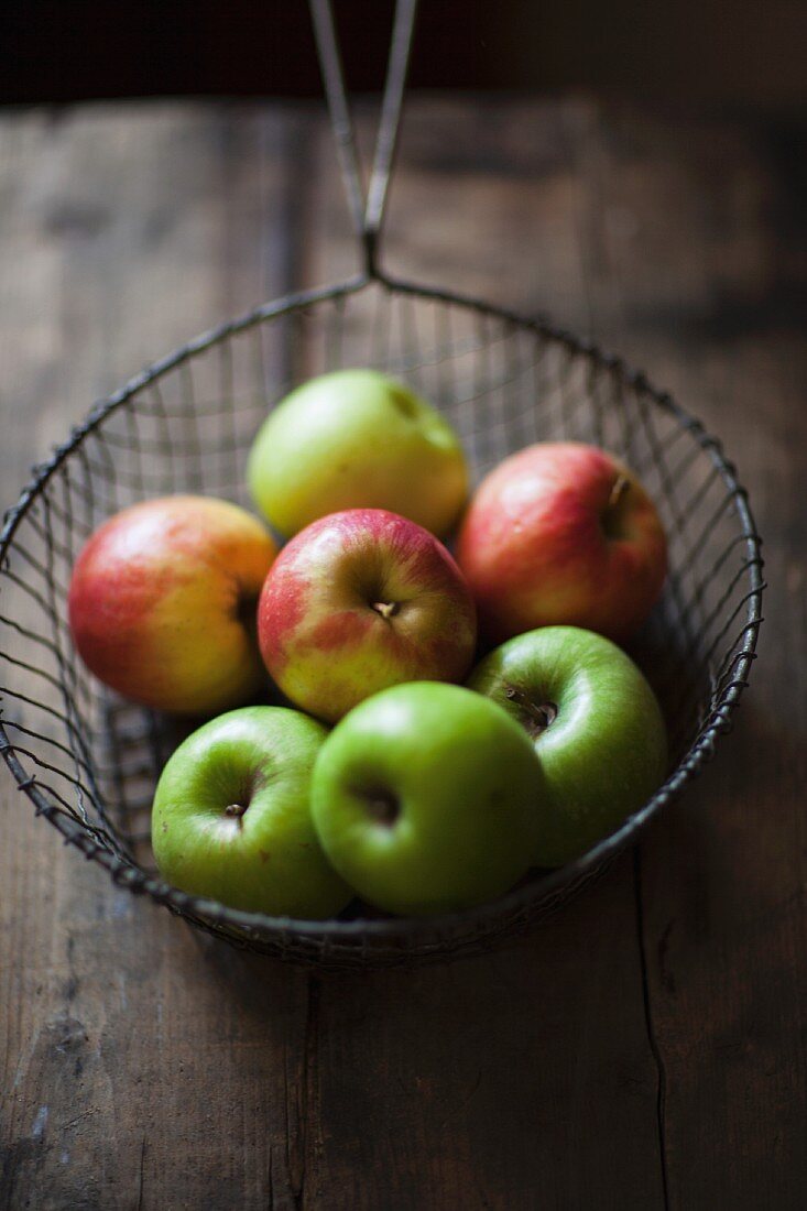 Various apples in a wire sieve