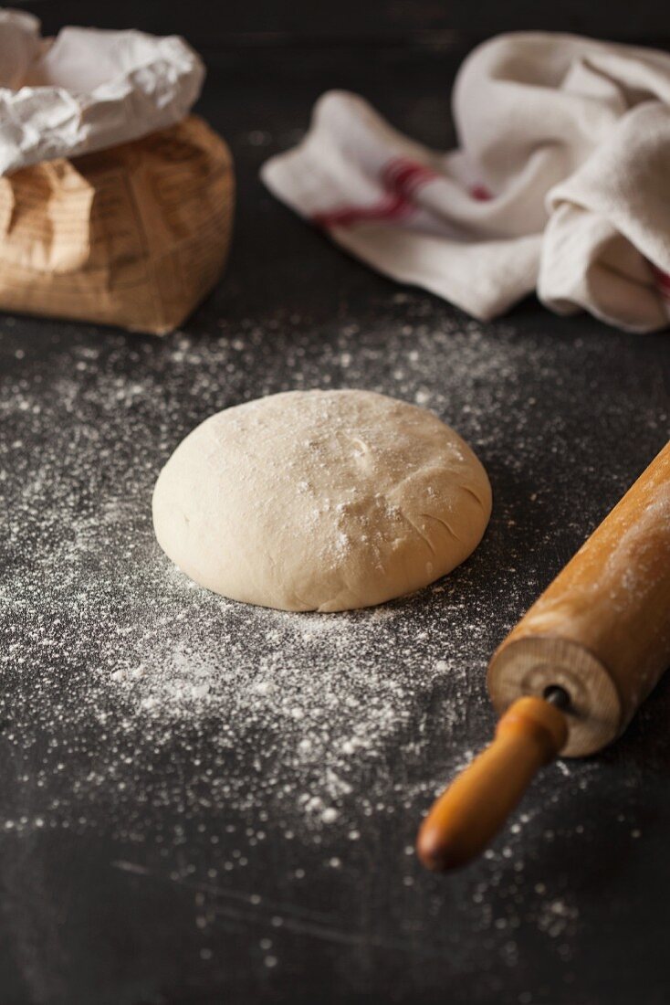 A ball of pastry, a rolling pin, flour and a tea towel