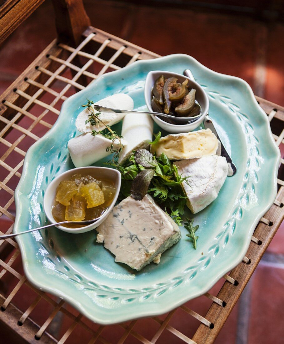 A cheese platter with herbs and pickles