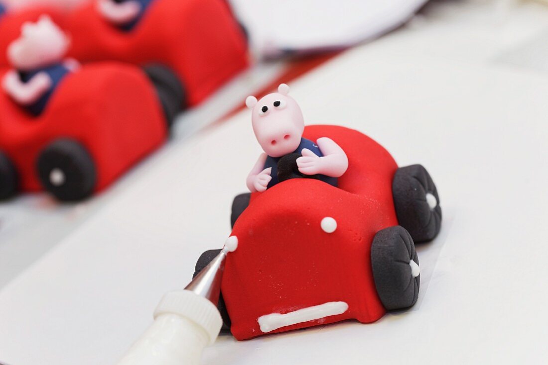 A fondant race car with a pig being finished
