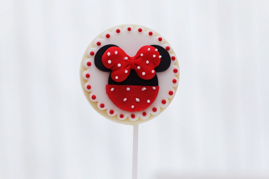 A round biscuit lolly decorated with a red bow and dots