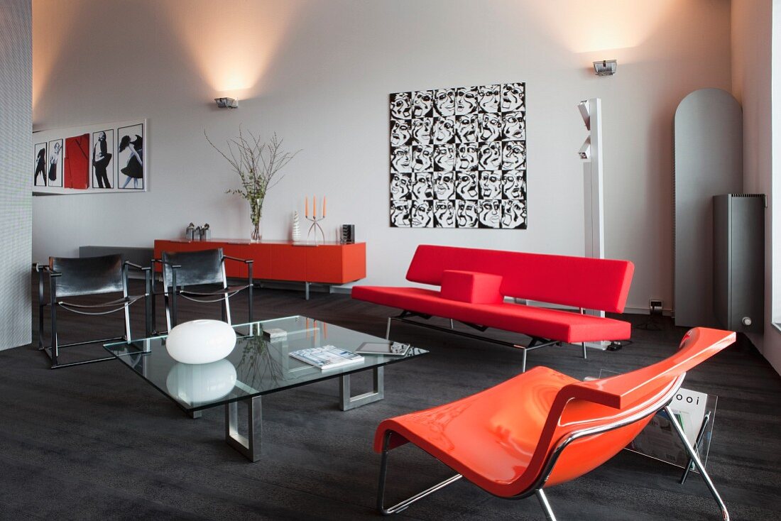Elegante Lounge mit Sitzmöbeln im Stilmix und in kräftigen Farbtönen, im Hintergrund Wandbeleuchtung in loftartigem Wohnraum