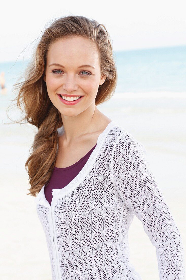 A young woman wearing a white lace jacket over a purple dress