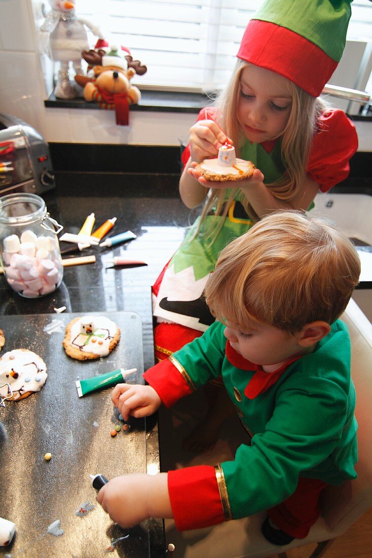 Kinder verzieren Weihnachtsplätzchen in der Küche