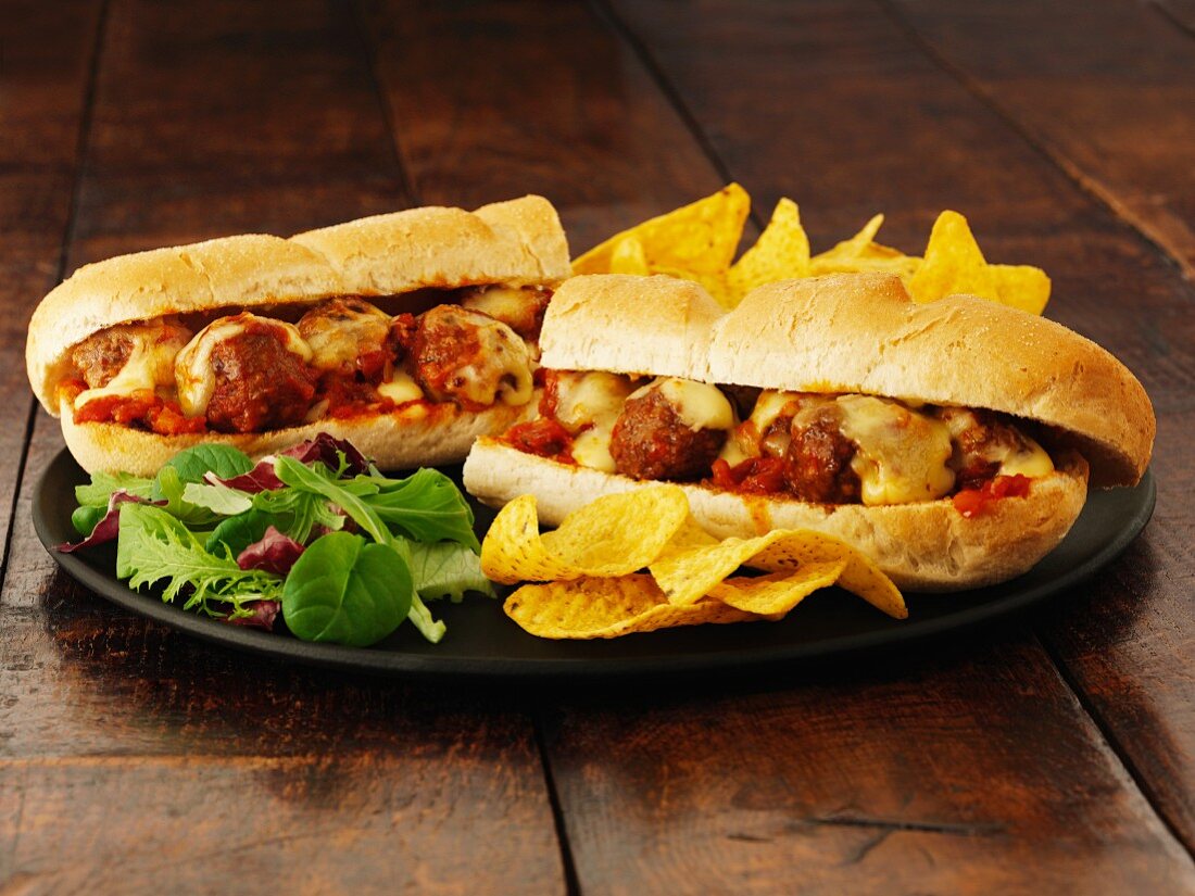 A meatball sub with cheese and crisps
