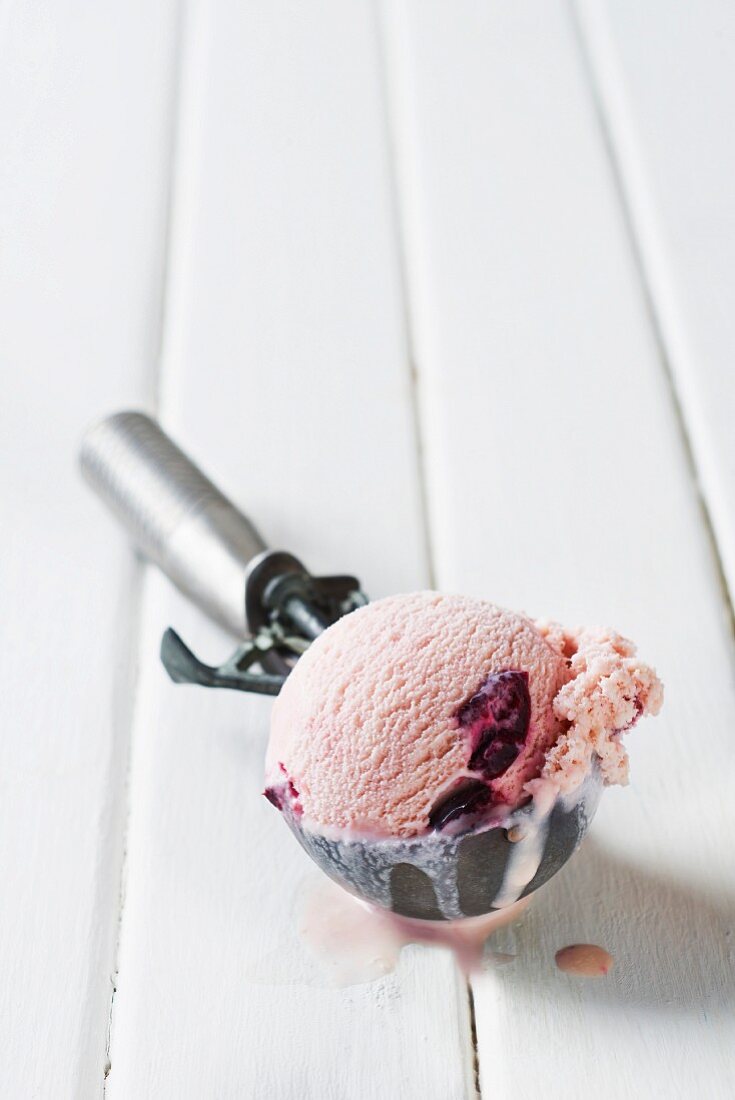 A scoop of cherry ice cream in an ice cream scoop
