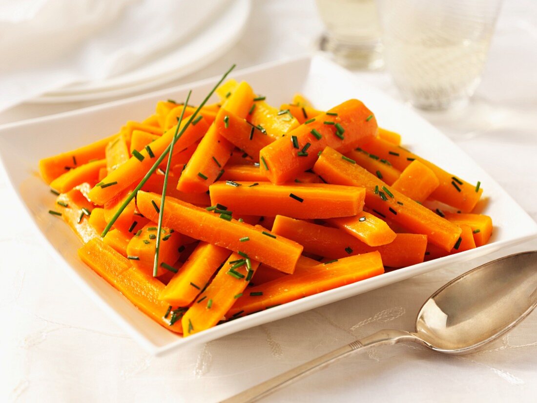 Karotten mit Butter und Schnittlauch, daneben Löffel
