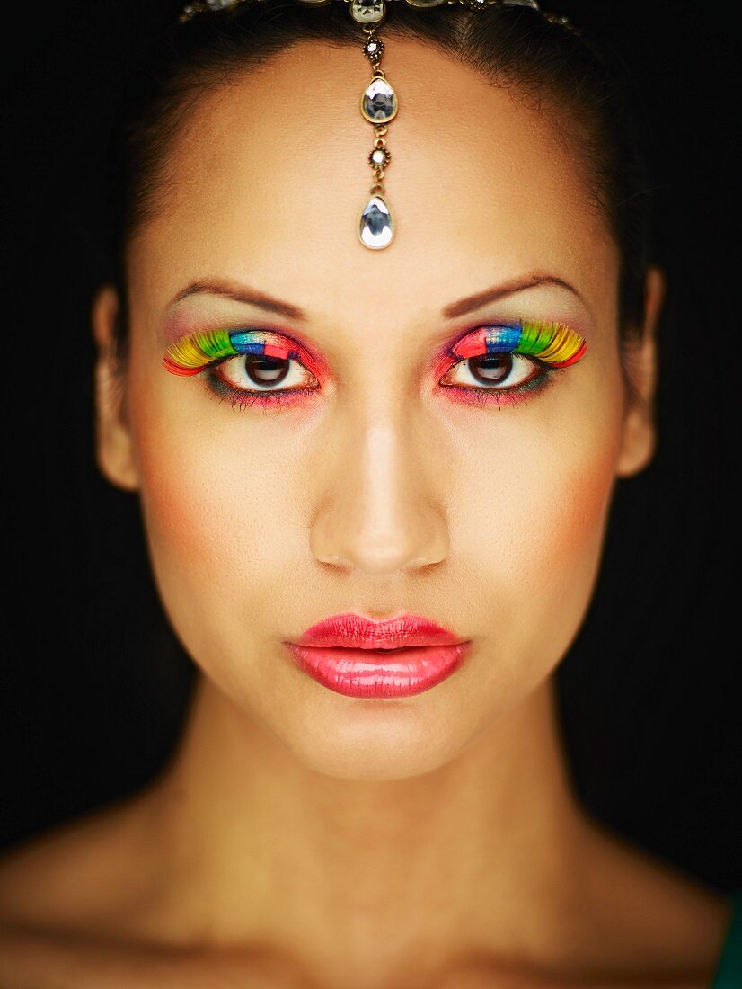 A young woman with colourful eyelashes and glittering head jewellery
