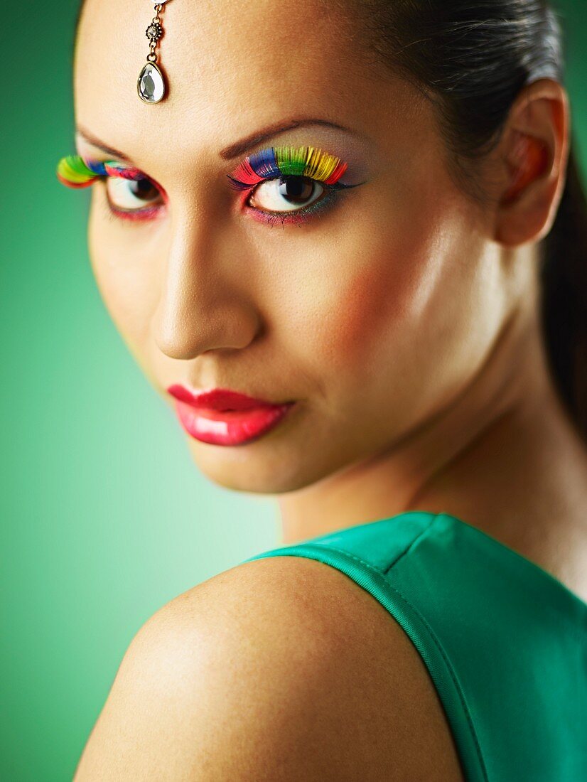 A young woman with colourful eyelashes and glittering head jewellery