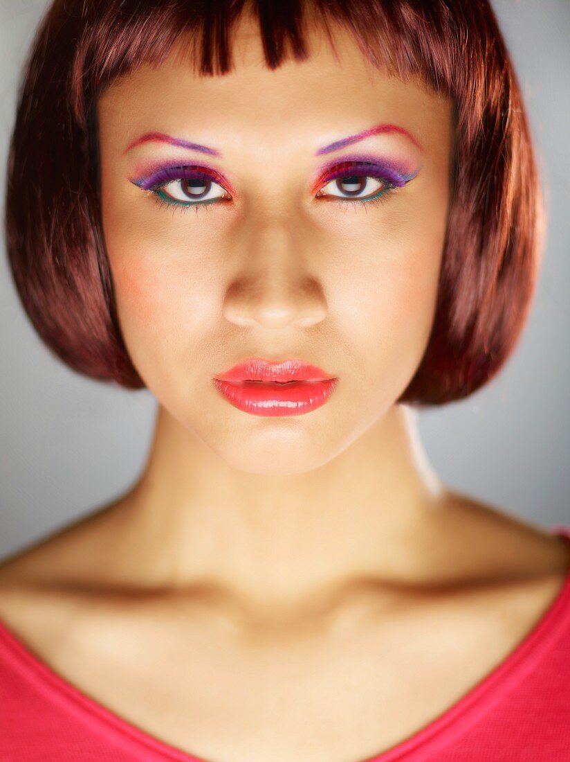 A young woman with red and violet eyeshadow and eyebrows
