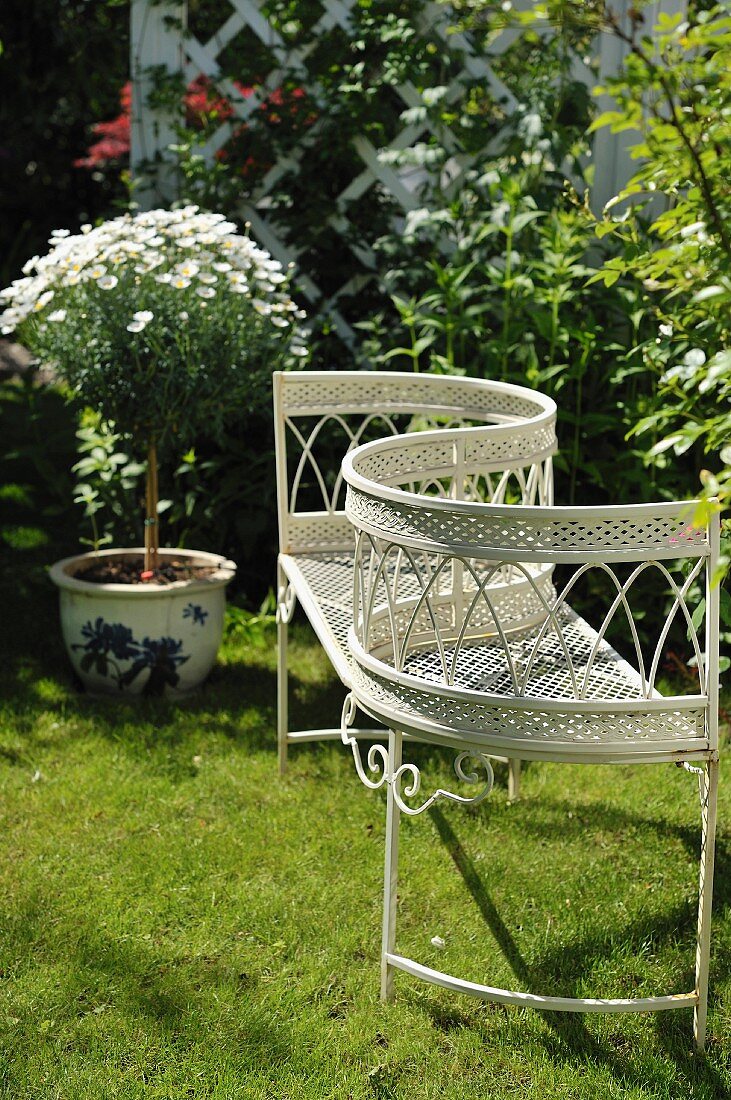 Delicate, white, metal garden kissing seat on lawn