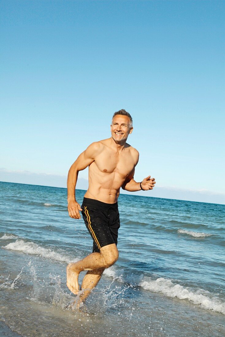 A middle-aged man jogging by the sea